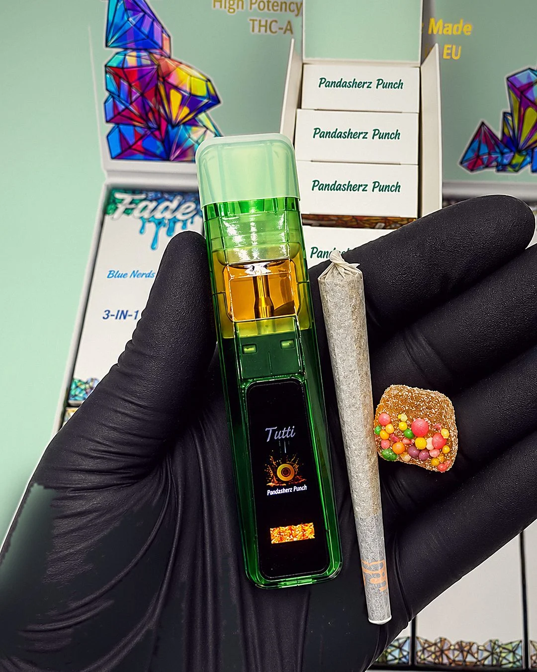 Fade 3-in-1 V3 Disposable pack in a gloved hand: green disposable vape, pre-roll and sugar-coated gummy